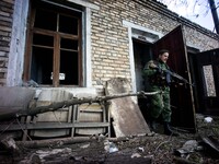 A DNR solider (formerly a traffic policeman before the war started) checks for tripwires and landmines in a destroyed building at a trolley...