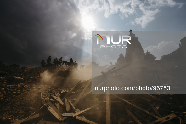 Rescue workers stand on top of a ruined temple and begin the process of carefully picking through the debris in search of survivors, Patan D...