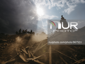 Rescue workers stand on top of a ruined temple and begin the process of carefully picking through the debris in search of survivors, Patan D...