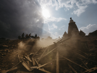 Rescue workers stand on top of a ruined temple and begin the process of carefully picking through the debris in search of survivors, Patan D...