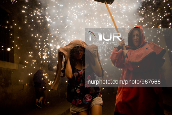 A reveler protects the head of the fire as a devil follows him   by the streets of the Raval district in Barcelona-Spain during a correfoc o...