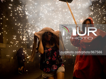 A reveler protects the head of the fire as a devil follows him   by the streets of the Raval district in Barcelona-Spain during a correfoc o...