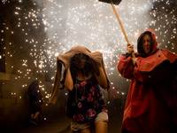 A reveler protects the head of the fire as a devil follows him   by the streets of the Raval district in Barcelona-Spain during a correfoc o...