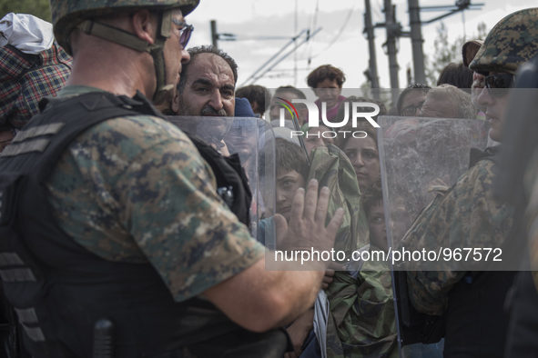 A young migrant looks through the cordon of police, where they are waiting on the Macedonian-Greek border where they are being held, since M...