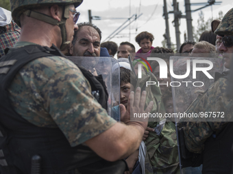 A young migrant looks through the cordon of police, where they are waiting on the Macedonian-Greek border where they are being held, since M...