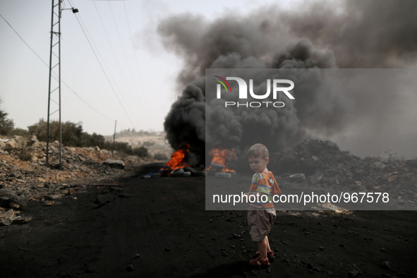 A Palestinian boy stands near a burning tyre during clashes with Israeli soldiers over the Jewish settlement of Qadomem in Kufr Qaddom villa...