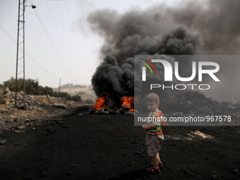 A Palestinian boy stands near a burning tyre during clashes with Israeli soldiers over the Jewish settlement of Qadomem in Kufr Qaddom villa...