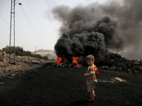 A Palestinian boy stands near a burning tyre during clashes with Israeli soldiers over the Jewish settlement of Qadomem in Kufr Qaddom villa...