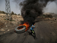 A Palestinian boy throws stones at Israeli forces during clashes with Israeli soldiers over the Jewish settlement of Qadomem at Kofr Qadom v...