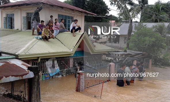 Residents sit on the rooftop of a flooded house in Nueva Ecija province, the Philippines, Oct. 19, 2015. Two people died and five other got...