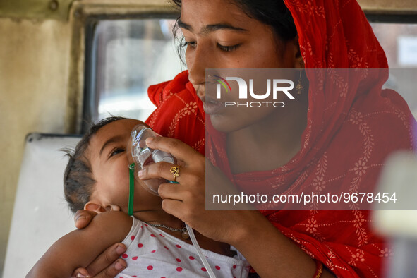 

A mother is holding an oxygen mask on the face of her child, who is suffering from respiratory distress, as seen in front of the emergency...