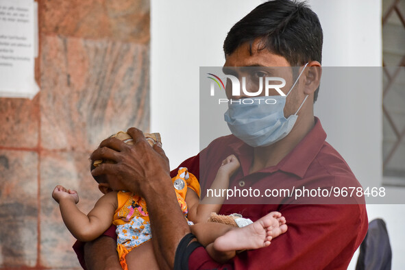 

A father is seen holding a napkin to his child's forehead, who is suffering from fever, in front of the emergency ward of a government-run...