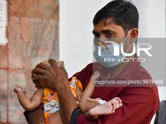 

A father is seen holding a napkin to his child's forehead, who is suffering from fever, in front of the emergency ward of a government-run...