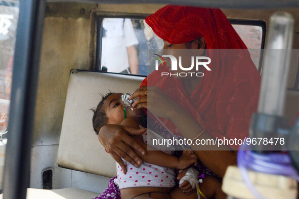 

A mother is holding an oxygen mask on the face of her child, who is suffering from respiratory distress, as seen in front of the emergency...