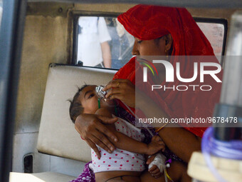 

A mother is holding an oxygen mask on the face of her child, who is suffering from respiratory distress, as seen in front of the emergency...