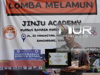 Aldo (17), posing for a photograph holding a champion's certificate after winning a daydream competition which was held in Solo, Central Jav...