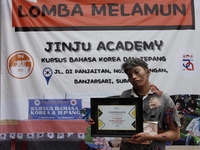 Aldo (17), posing for a photograph holding a champion's certificate after winning a daydream competition which was held in Solo, Central Jav...