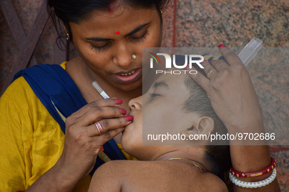 A woman checks the temperature of her six-year-old daughter, who is suffering from fever, with a thermometer, at a hospital in Kolkata on Ma...