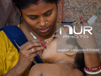 A woman checks the temperature of her six-year-old daughter, who is suffering from fever, with a thermometer, at a hospital in Kolkata on Ma...