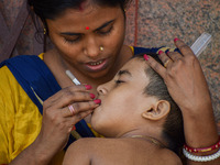 A woman checks the temperature of her six-year-old daughter, who is suffering from fever, with a thermometer, at a hospital in Kolkata on Ma...