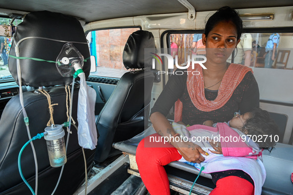 A woman holds a five-month-old child, who is suffering from respiratory problems, inside an ambulance, at a hospital in Kolkata on March 06,...