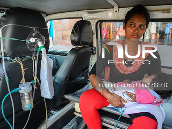 A woman holds a five-month-old child, who is suffering from respiratory problems, inside an ambulance, at a hospital in Kolkata on March 06,...