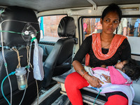 A woman holds a five-month-old child, who is suffering from respiratory problems, inside an ambulance, at a hospital in Kolkata on March 06,...