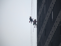 

Workers are hanging on by the rope as they clean the windows of a high-lying building in the Nepali capital, Kathmandu, on March 15th, 202...