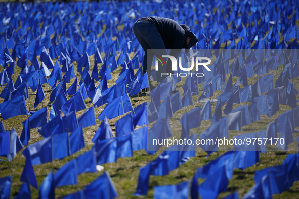 A man places flags at a visual exhibit organized by the Fight Colorectal Cancer organization on the National Mall in Washington, D.C. on Mar...