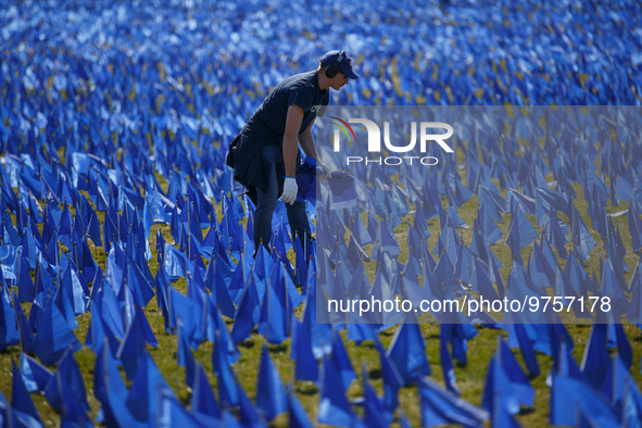 A man places flags at a visual exhibit organized by the Fight Colorectal Cancer organization on the National Mall in Washington, D.C. on Mar...