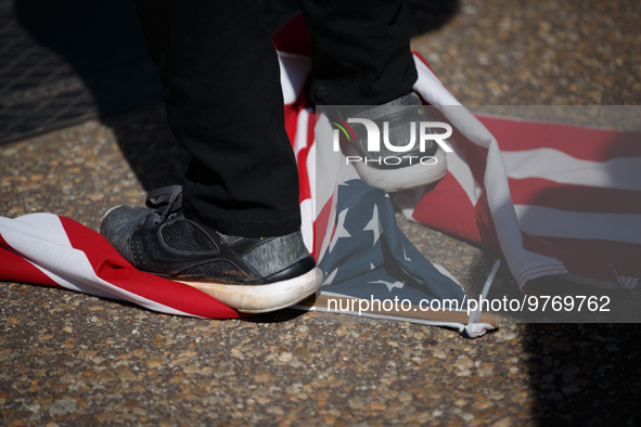 A demonstrator stands on a United States flag during an anti-war protest in Washington, D.C. on March 18, 2023. The protest, organized by th...