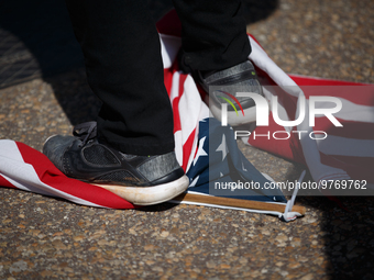 A demonstrator stands on a United States flag during an anti-war protest in Washington, D.C. on March 18, 2023. The protest, organized by th...