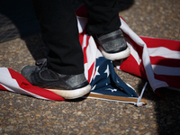 A demonstrator stands on a United States flag during an anti-war protest in Washington, D.C. on March 18, 2023. The protest, organized by th...