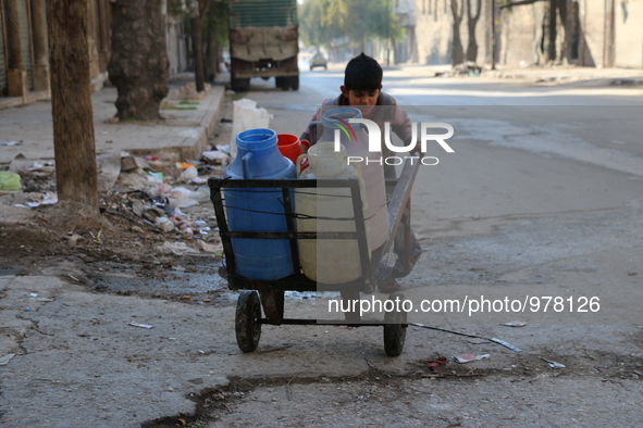 A Syrian boy pushes a cart with jerrycans filled with water in Aleppo on December 30, 2015 as residents of the northern city suffer constant...