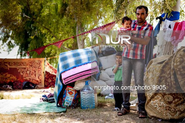 A young father of two kids with his improvised "home" in the background and his goods and chattels. He´s living with his family in an open s...