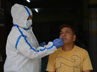 A healthcare worker collects a swab sample of a man for Covid-19 test, amid a rise in coronavirus cases in the country, in New Delhi on Apri...