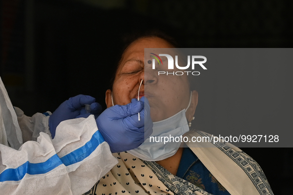 A healthcare worker collects a swab sample of a woman for Covid-19 test, amid a rise in coronavirus cases in the country, in New Delhi on Ap...