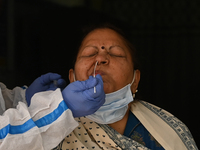 A healthcare worker collects a swab sample of a woman for Covid-19 test, amid a rise in coronavirus cases in the country, in New Delhi on Ap...